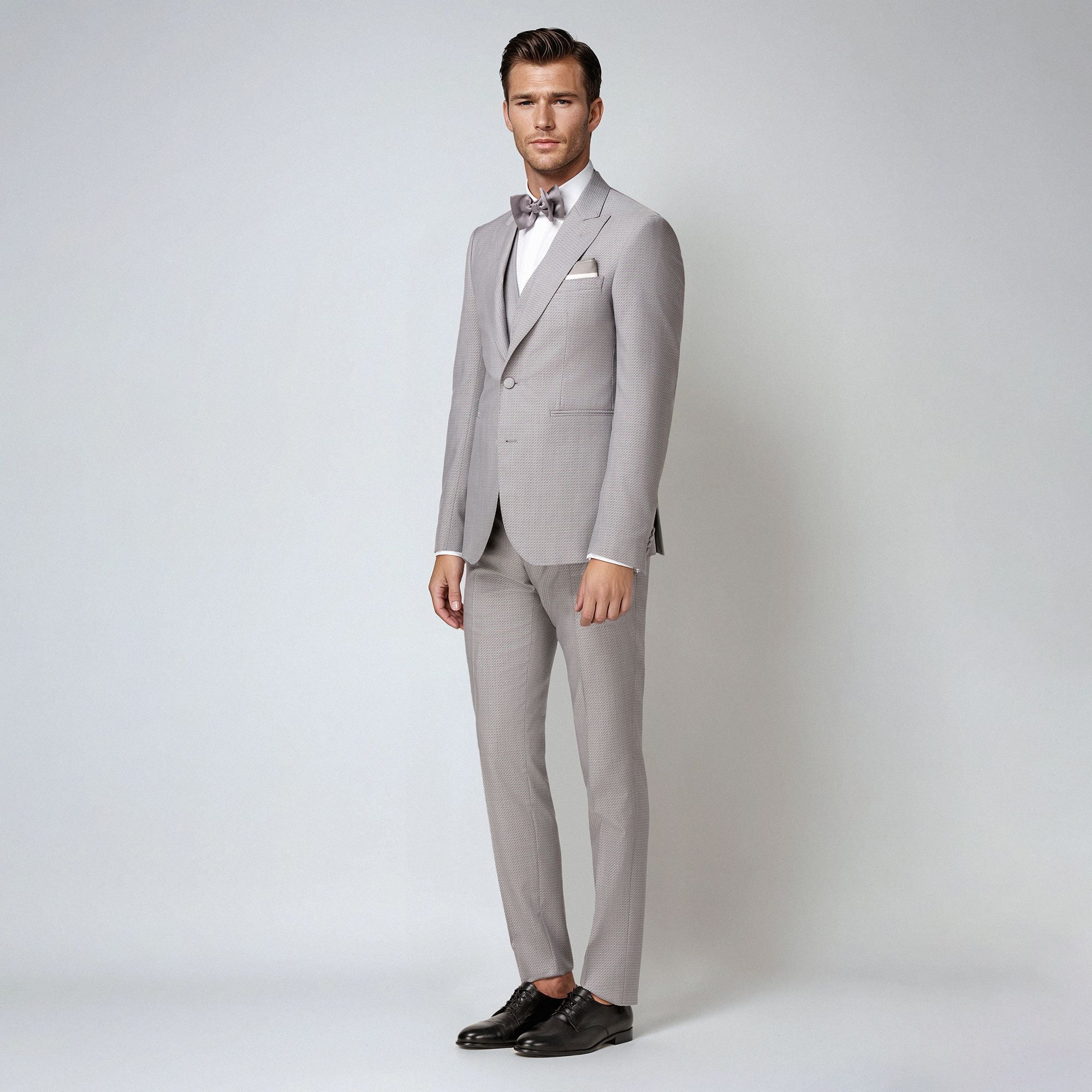 A refined grey jacquard three-piece suit in wool-silk blend. Peak lapel jacket, fabric-covered buttons & sartorial tailoring. Made in Italy.