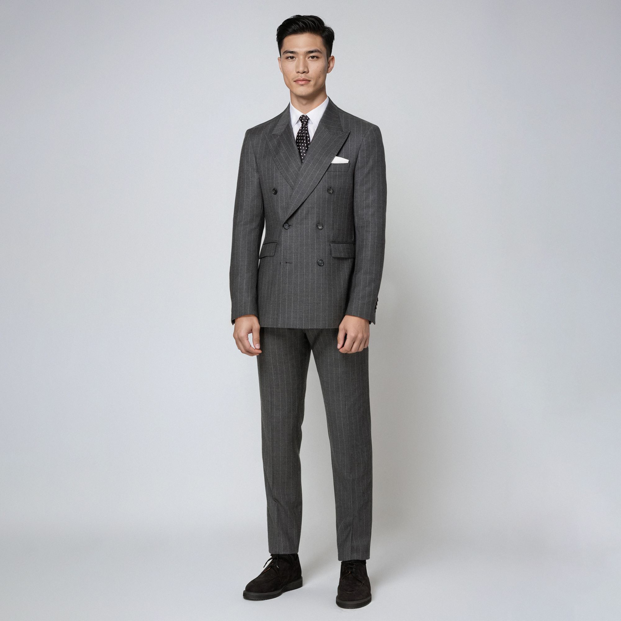 Man in an Elio Evan total look wearing a grey pinstripe wool double-breasted suit, white shirt and tie.