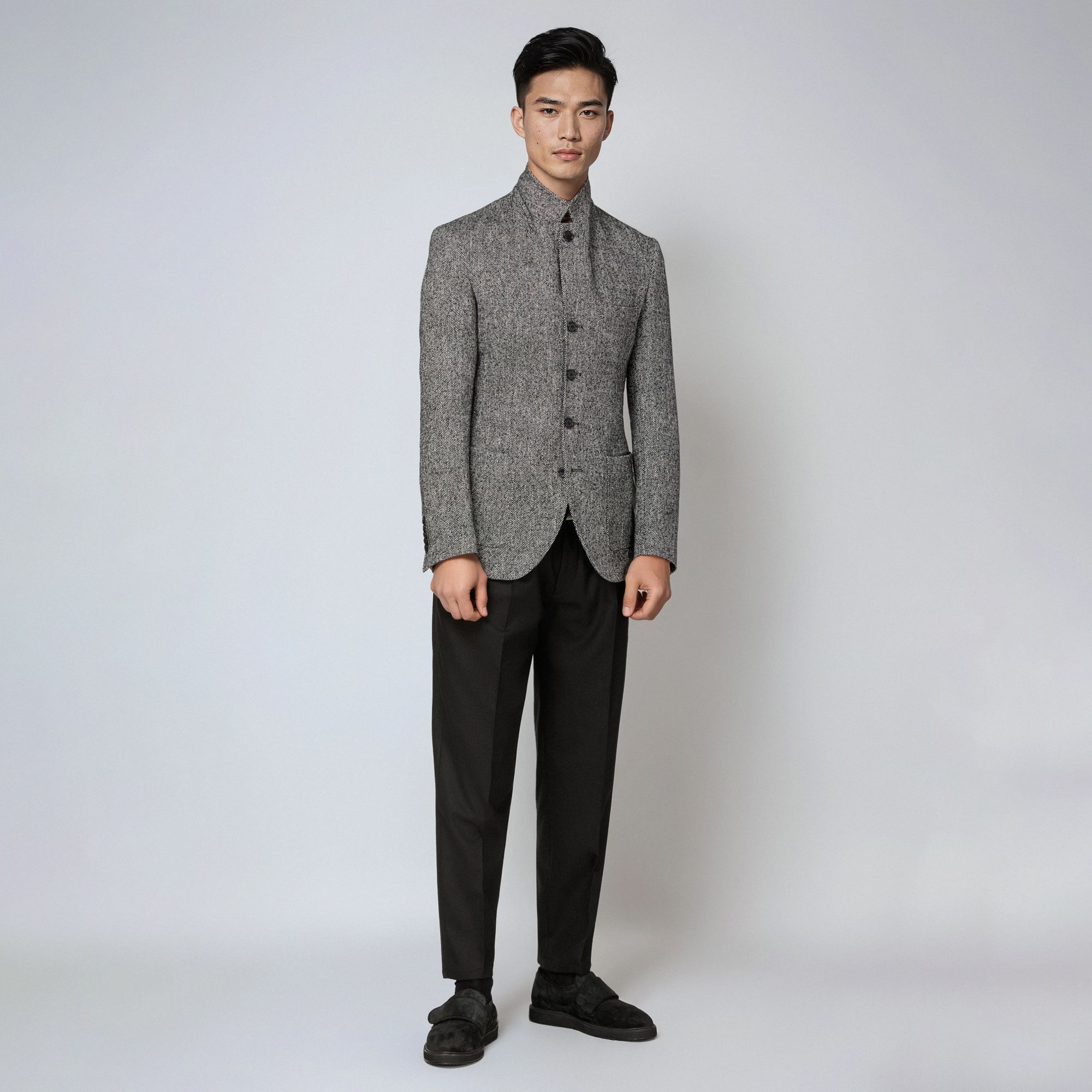 Man wearing an Elio Evan total look with a grey bouclé jacket buttoned up and black trousers.