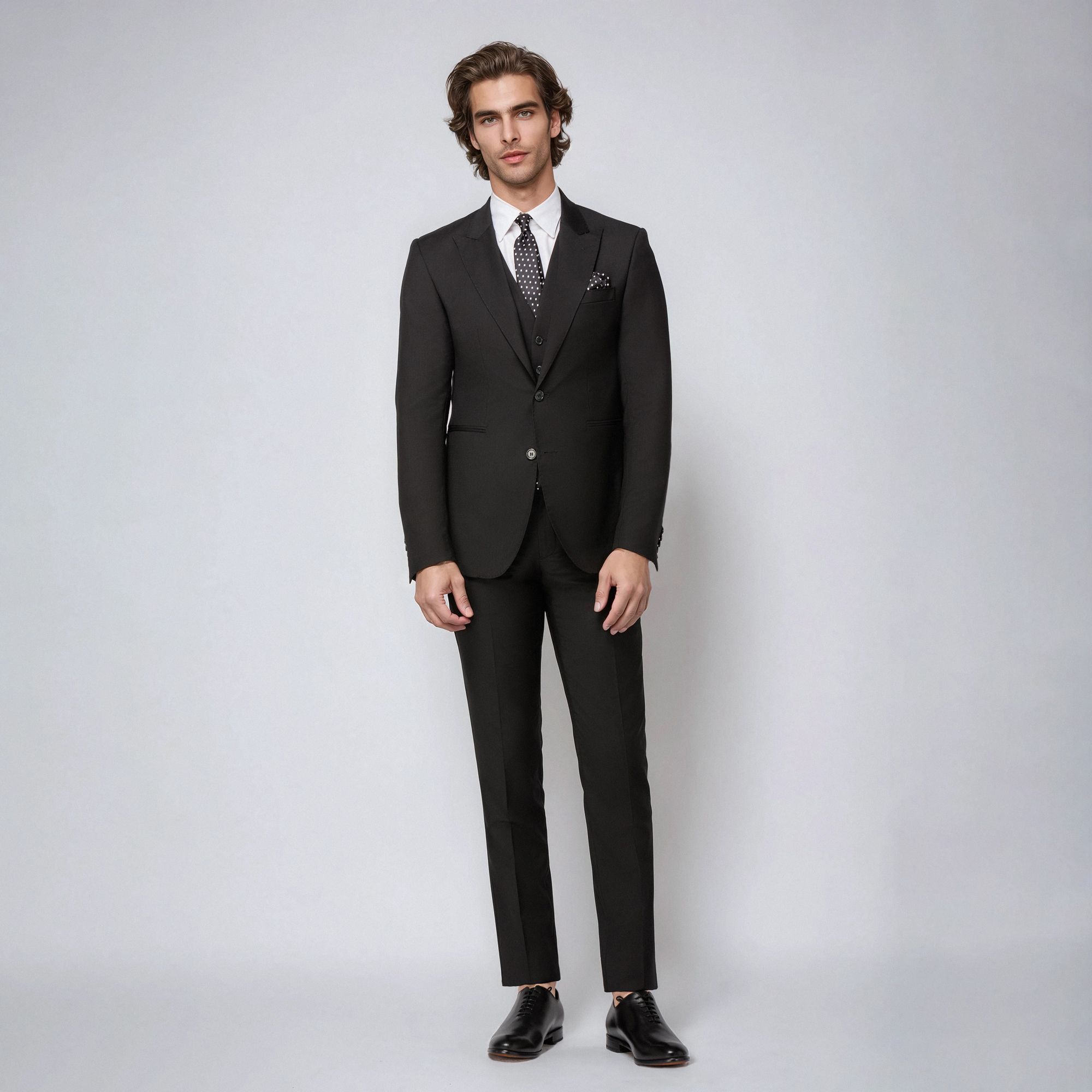 Elio Evan black three-piece suit with peak lapels and gold emblem. Slim Bristol fit. Made in Italy