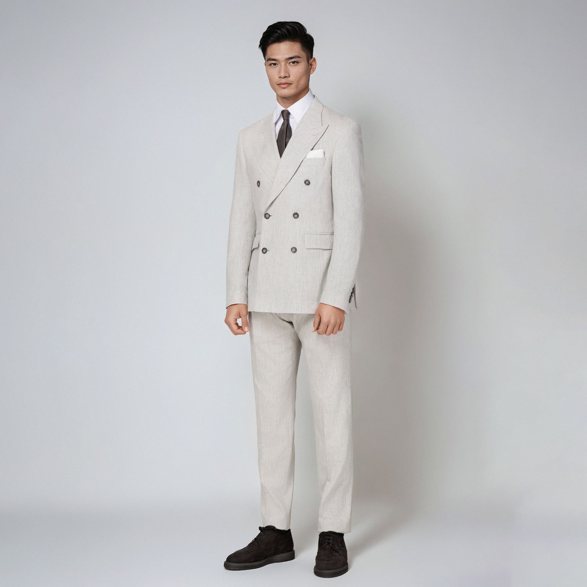 Elio Evan’s light grey mélange double-breasted suit in virgin wool and cashmere. Modern Italian tailoring with peak lapels and tailored trousers.