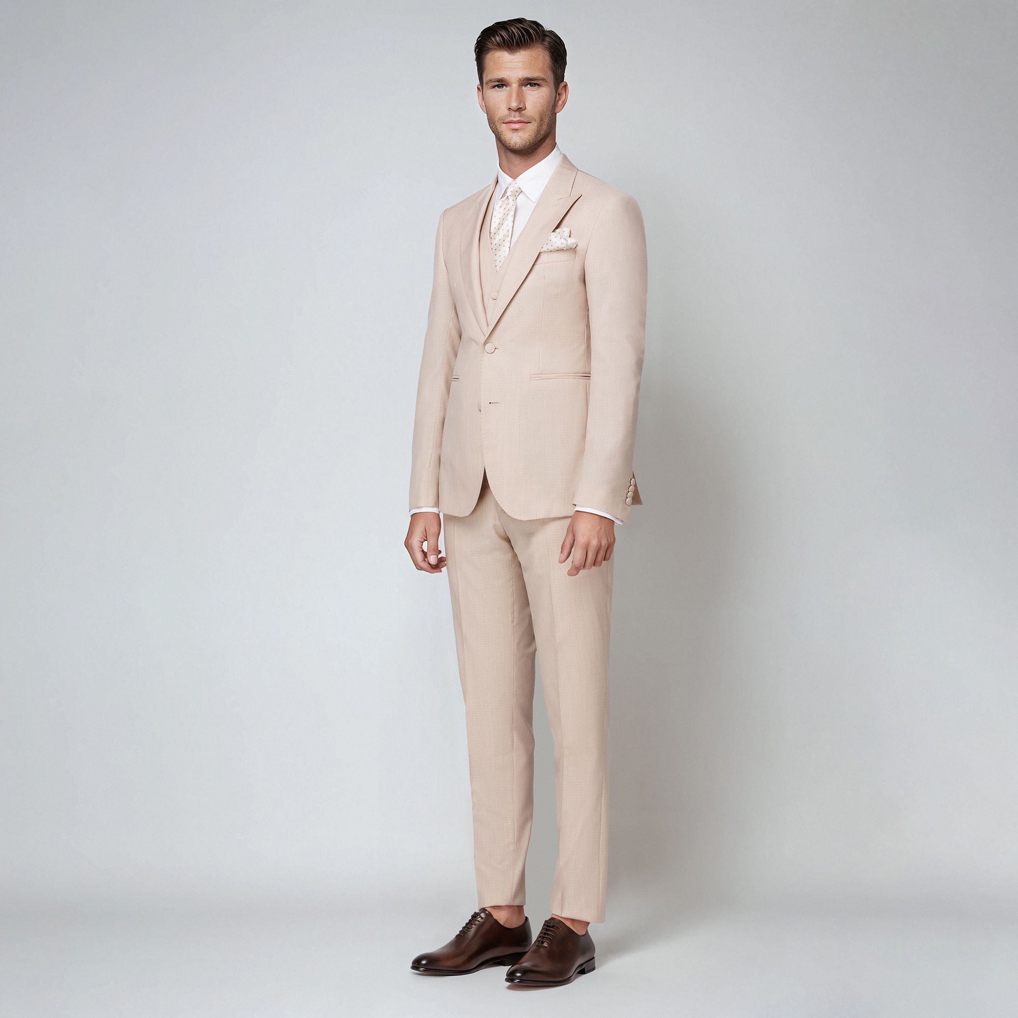 A refined beige jacquard three-piece suit in a wool-silk blend. Peak lapel jacket, fabric-covered buttons & sartorial tailoring. Made in Italy.