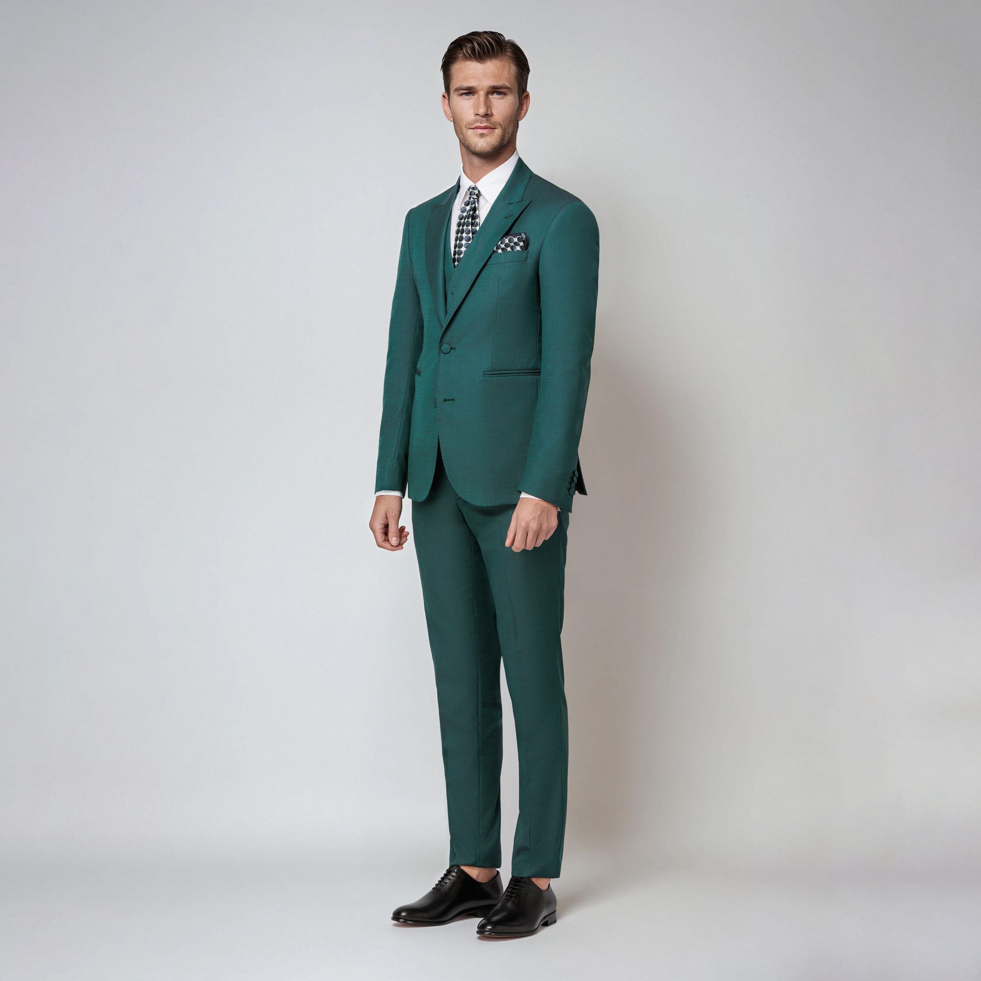 A refined green iridescent three-piece suit in a wool-silk blend. Peak lapel jacket, fabric-covered buttons & sartorial tailoring. Made in Italy.