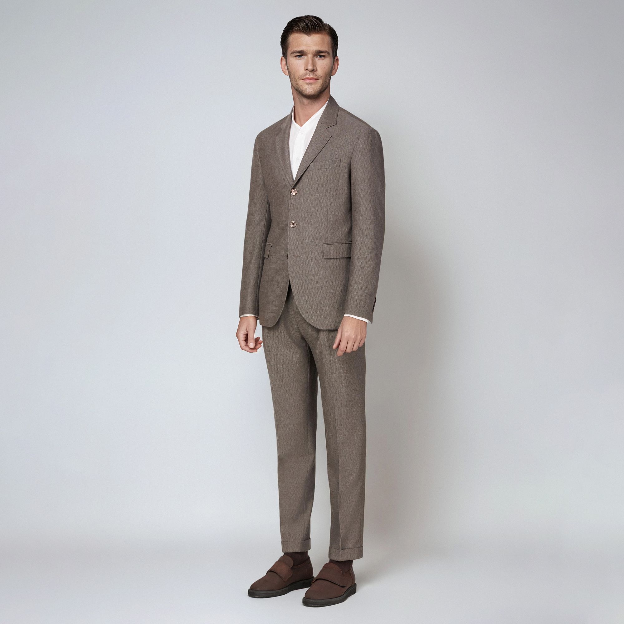 Man wearing Elio Evan total look: taupe wool men’s suit, white shirt – elegant formal outfit.